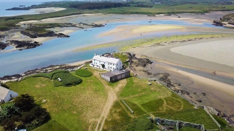 Aerial view of Hen Cymyran on the headland, surrounded by sand and sea