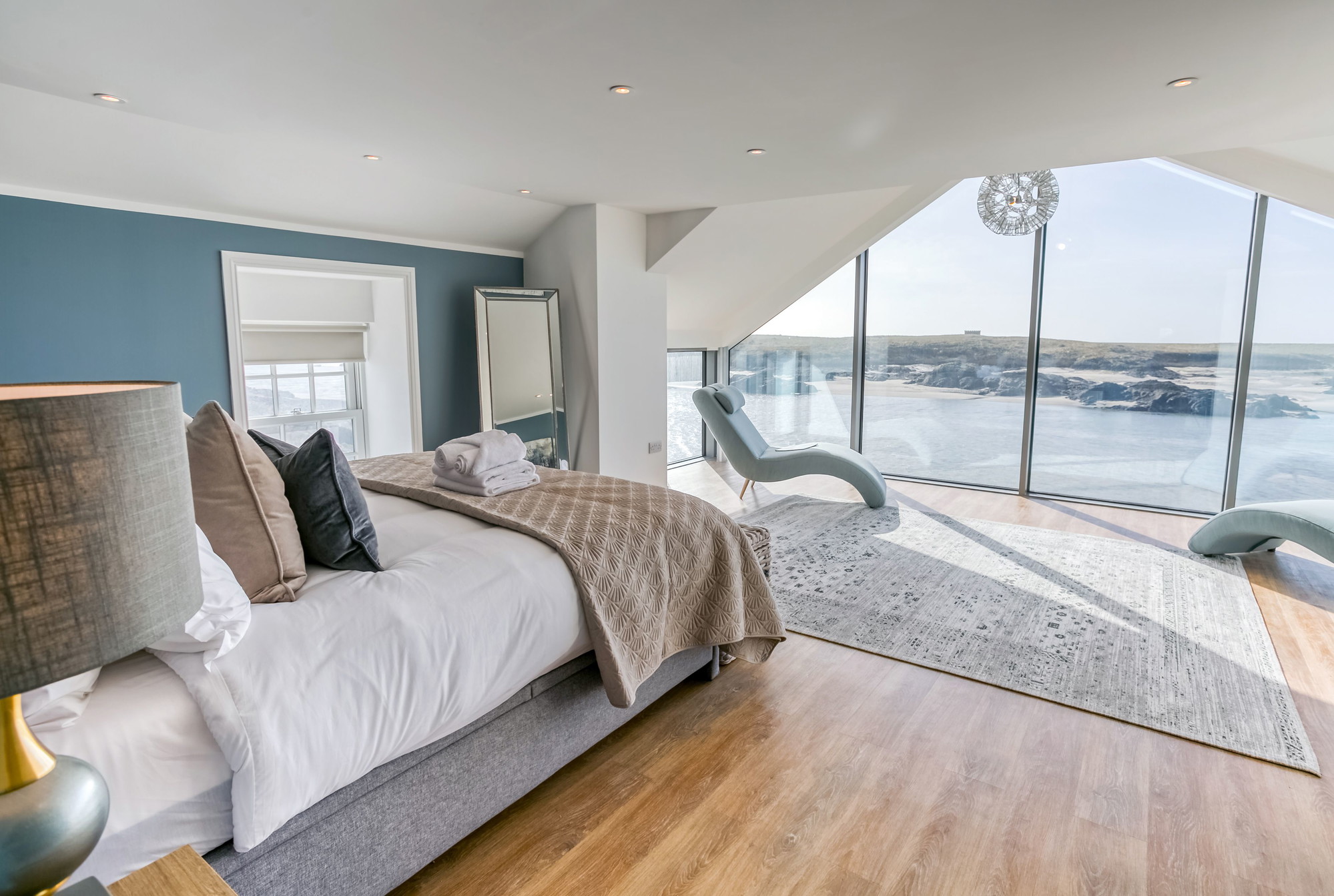 The main bedroom with a super king bed facing vast windows of sea and sky